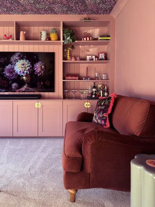 blush pink built-in cupboards with cherry red velvet loveseat and soft cream carpet